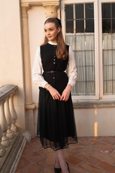 a lady in a white shirt, a black vest with a belt and a black tulle skirt
